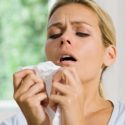 Woman holding a tissue with a distressed expression, emphasizing the need for effective HVAC filters during allergy season.