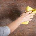 Hand cleaning a wooden surface with a yellow cloth, relevant for HVAC maintenance by Jerry Brittingham A/C & Heat, Inc.