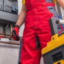 Person in red overalls with tools in an industrial setting for Jerry Brittingham A/C & Heat HVAC services.