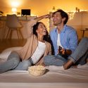 Couple enjoying popcorn and remote control in a cozy living room, reflecting relaxation and comfort at home.