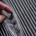 Close-up of a hand examining pleated gray fabric, showcasing detailed texture for HVAC material quality insights.