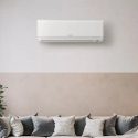 Wall-mounted air conditioner in a modern living space with cushions and a potted plant, by Jerry Brittingham A/C & Heat, Inc.