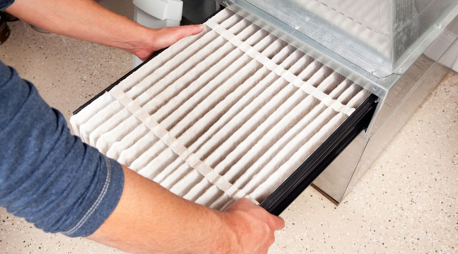 Hands removing a clean air filter, highlighting HVAC maintenance by Jerry Brittingham A/C & Heat, Inc.