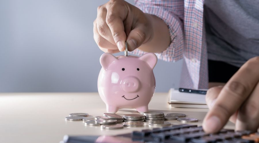 Pink piggy bank with a smiling face, coins, and a calculator, representing HVAC financial responsibility and savings.
